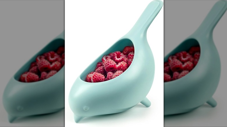 Light blue bird-shaped colander filled with raspberries
