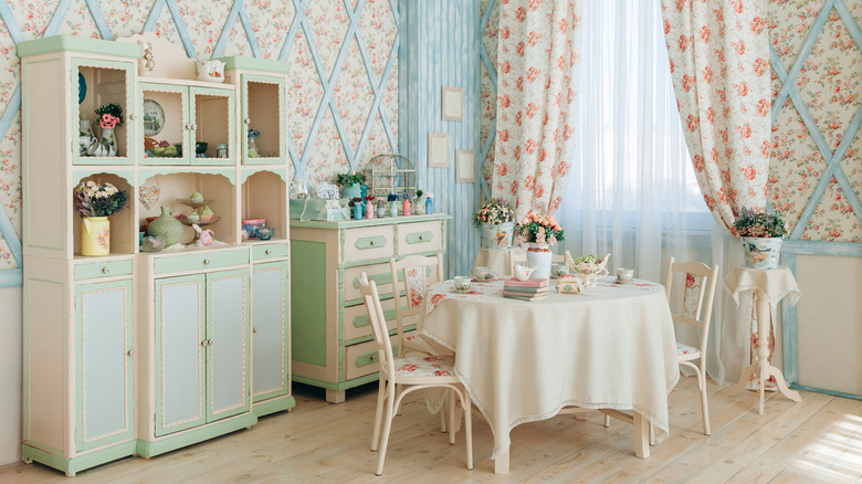 Vintage-style kitchen with light wooden floors, floral decor, and mint green and white cabinetry