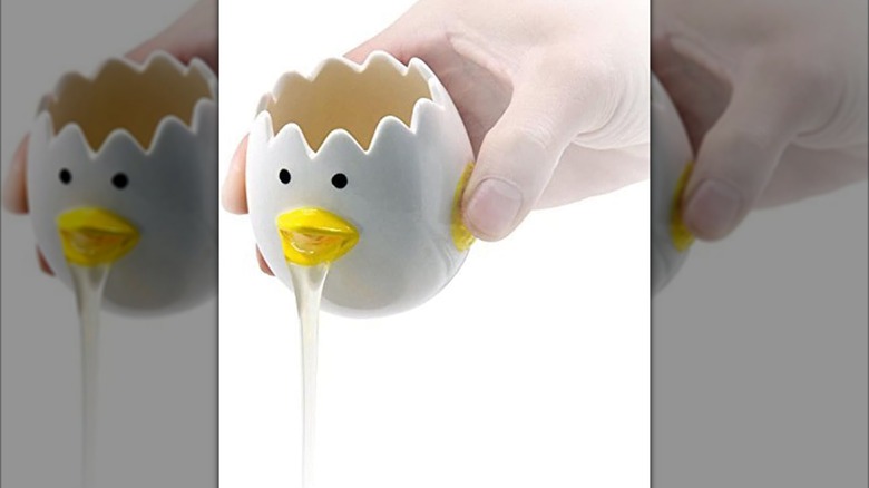 Egg-shaped egg yolk separator with black dots for eyes and a yellow chicken beak expelling egg white