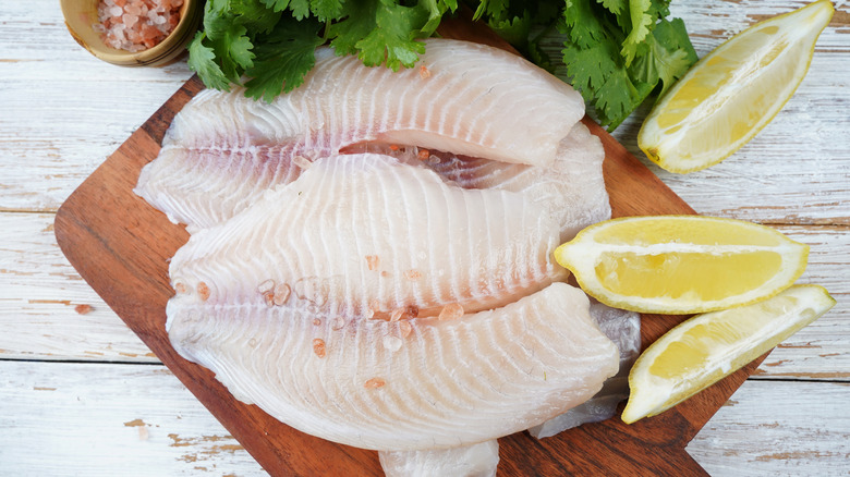 Fresh tilapia on a board with lemons
