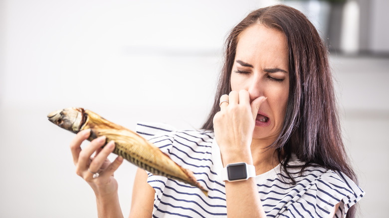 A woman holding her nose while looking at a fish