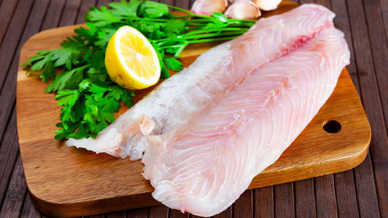 A raw perch fillet on board with lemons