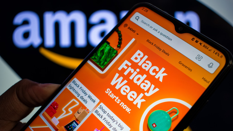 man holds phone with Amazon black friday deals