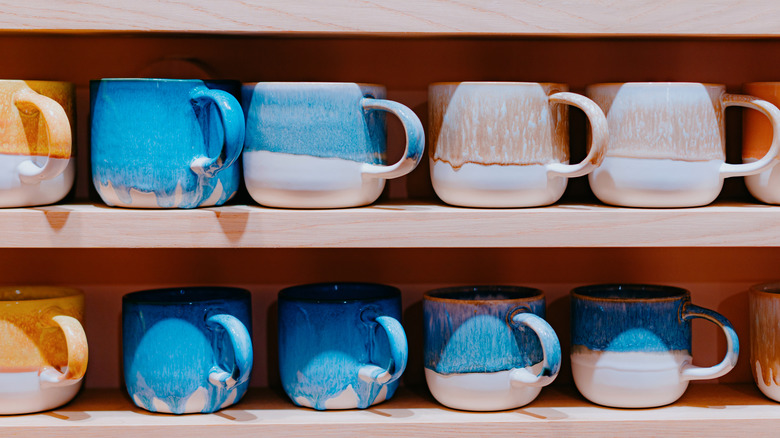 A shelf of ceramic mugs of various colors