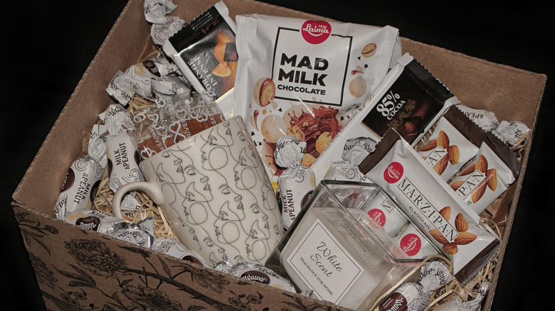 A gift set containing various chocolates, a candle, and a mug