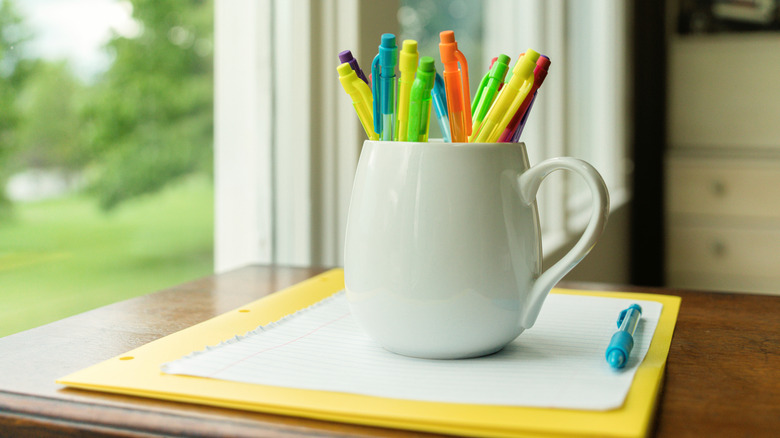 A coffee mug holding a colorful bunch of pens