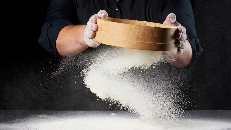 Baker using a drum sieve for flour