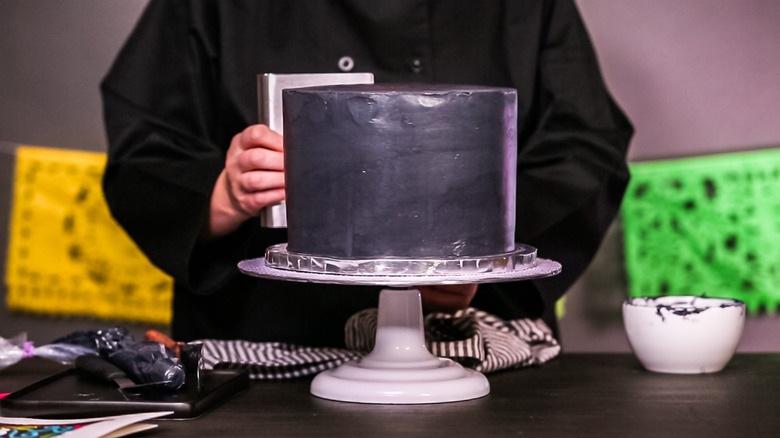 Baker using a rotating cake stand to ice cake