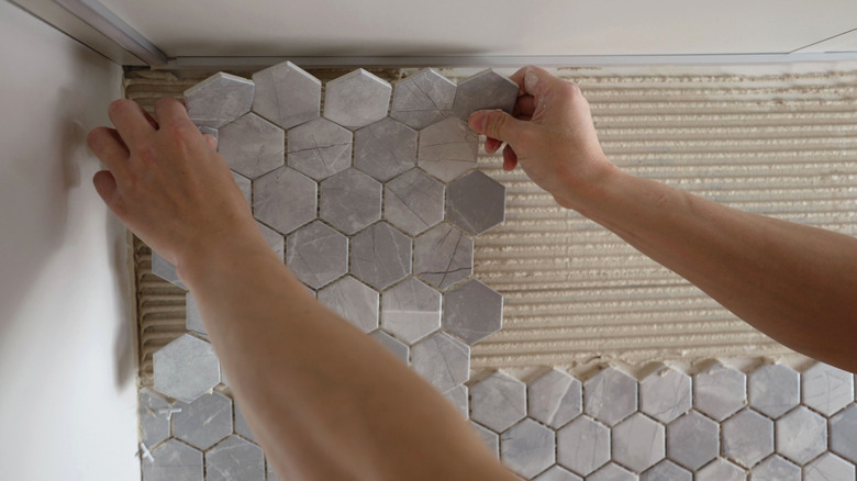 A person applying a peel-and-stick backsplash