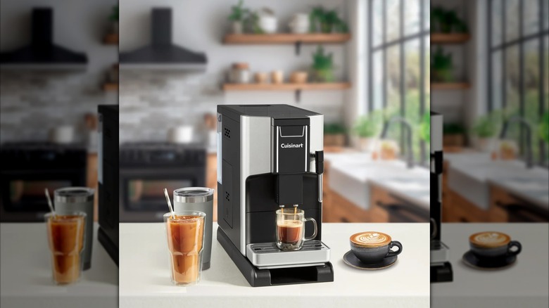 A Cuisinart automatic espresso machine on a kitchen counter with various coffee drinks sitting around it.
