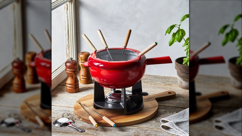 A bright red fondue set with several fondue forks sticking out of it.