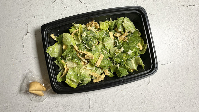 P.F. Chang's Asian Caesar Salad in a takeout container next to a fortune cookie