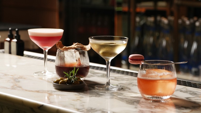 4 cocktails sit on a marbled bar