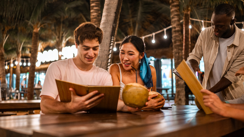 People engaging with a menu at a outdoor bar