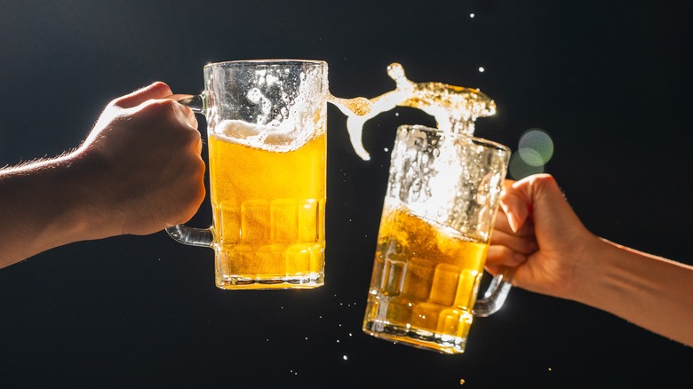 Two glasses of beer splashing mid-cheers