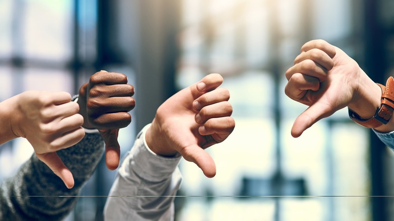 Four hands showing thumbs down