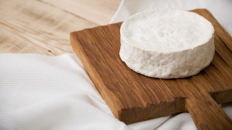 Small wheel of Brie cheese on cutting board