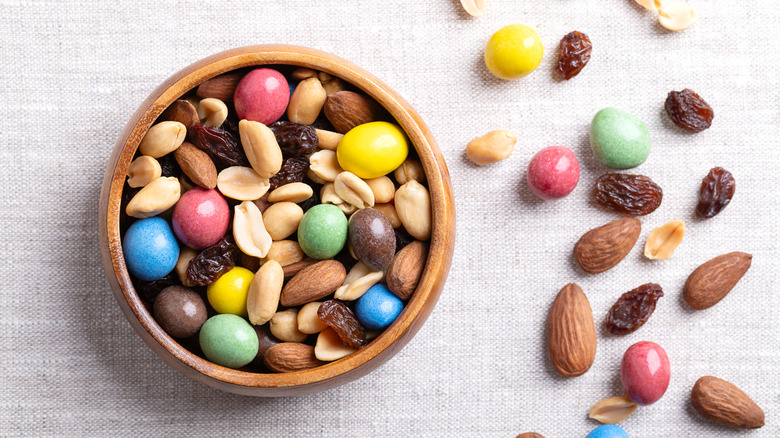 Wooden bowl of trail mix with some spilling out