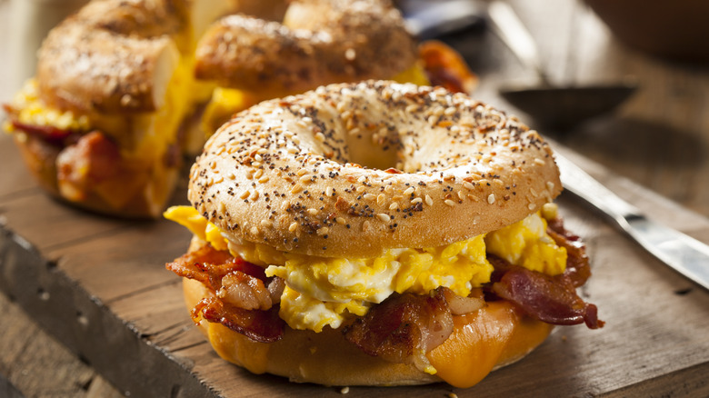 a close-up of a breakfast bagel with scrambled eggs and bacon