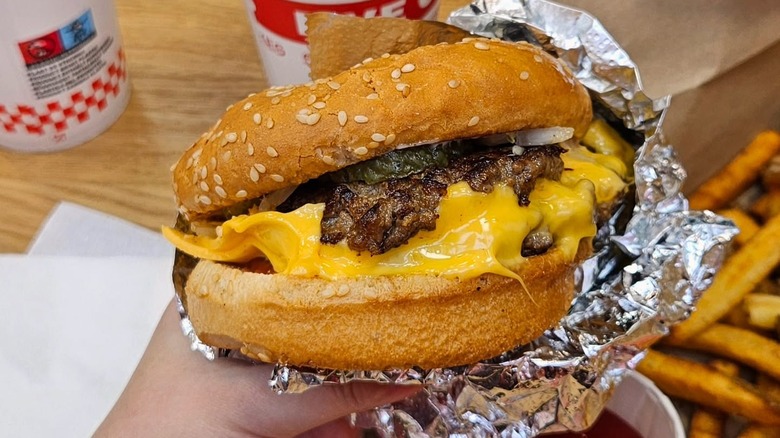 A person holding a Five Guys hamburger