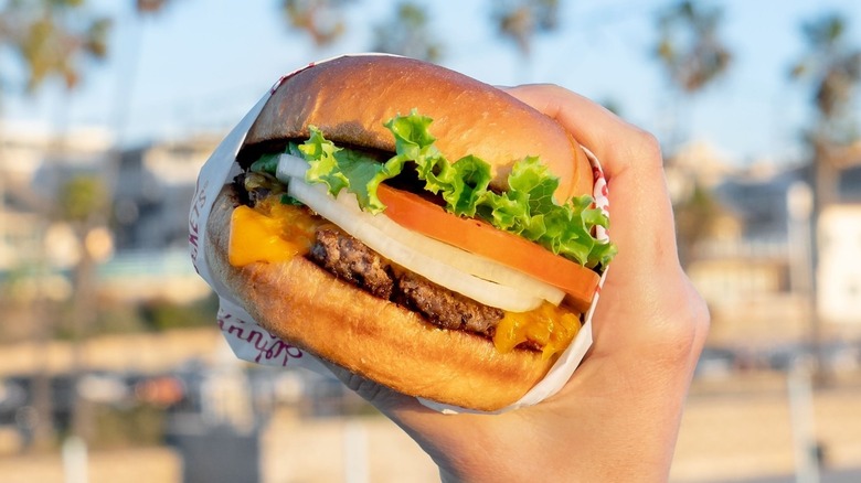 A person holding a Johnny Rockets hamburger