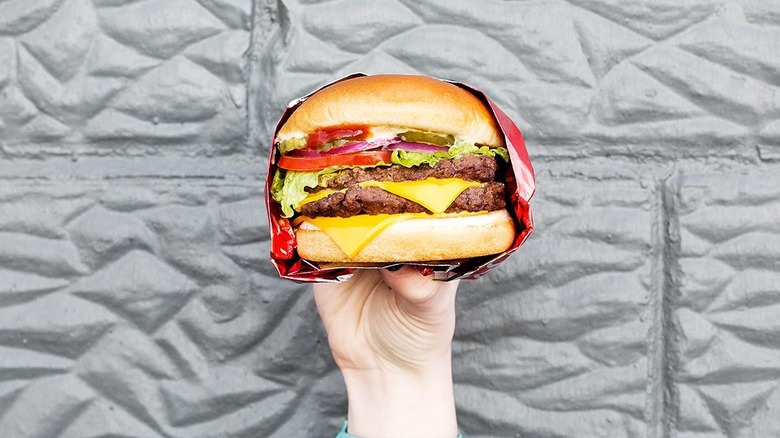 A person holding a Wendy's cheesburger