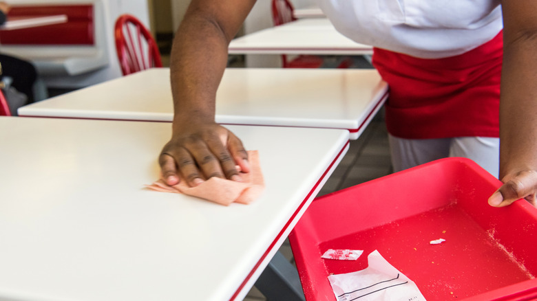Employee cleaning a dirty tabletop
