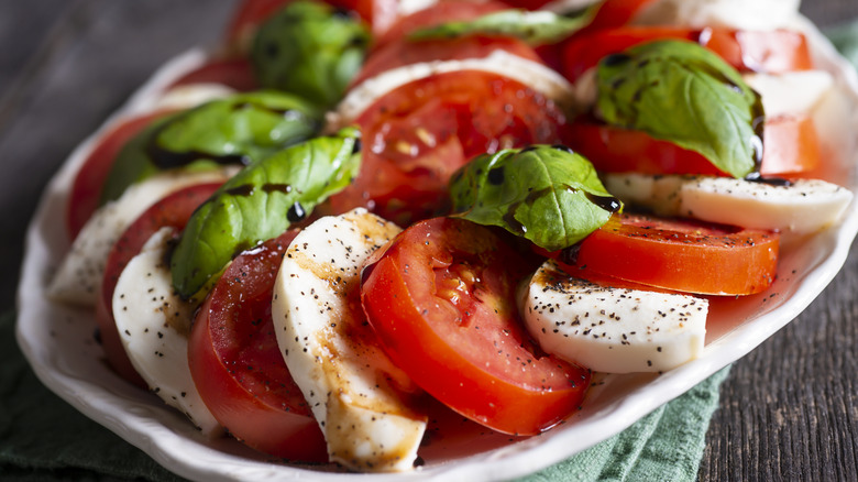 Plate of caprese salad with mozzarella, tomatoes, basil, and balsamic