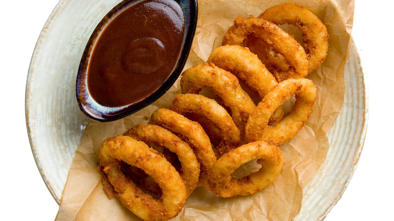Plate of onion rings with a dish of BBQ sauce