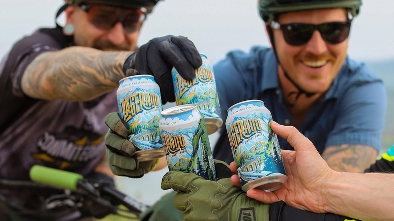 People in biking gear toasting with cans of Odell Lagerado Crispy Lager