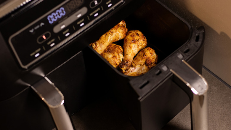 Air fryer on a counter with chicken in the basket