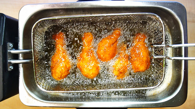 Person frying chicken in a countertop deep-fryer