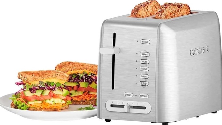 Cuisinart's Custom Select 2-Slice toaster with slices of bread popping out and a sandwich on a plate to the left