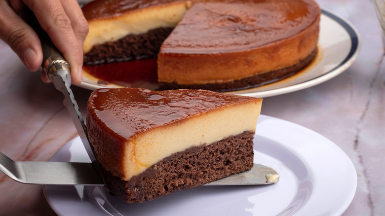 A person placing a slice of chocoflan cake on a plate