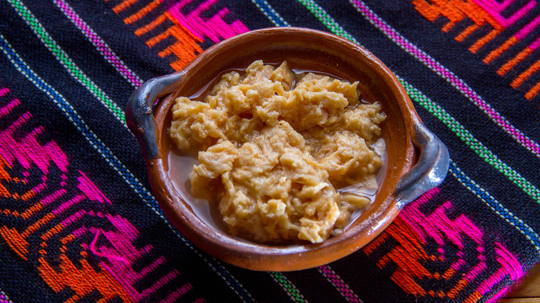 A bowl of chongos zamoranos on a colorful tablecloth
