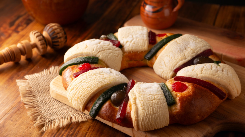 A rosca de reyes cake on a wooden cutting board
