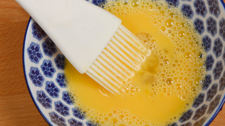 A pastry brush in a bowl of egg wash