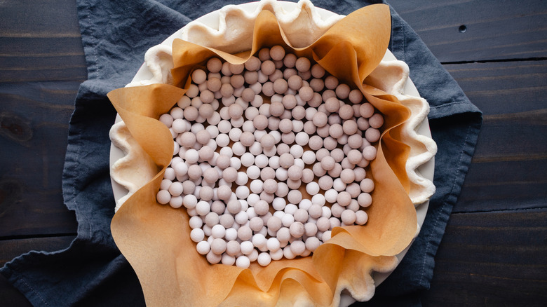 A pie crust lined with parchment paper and filled with dried beans