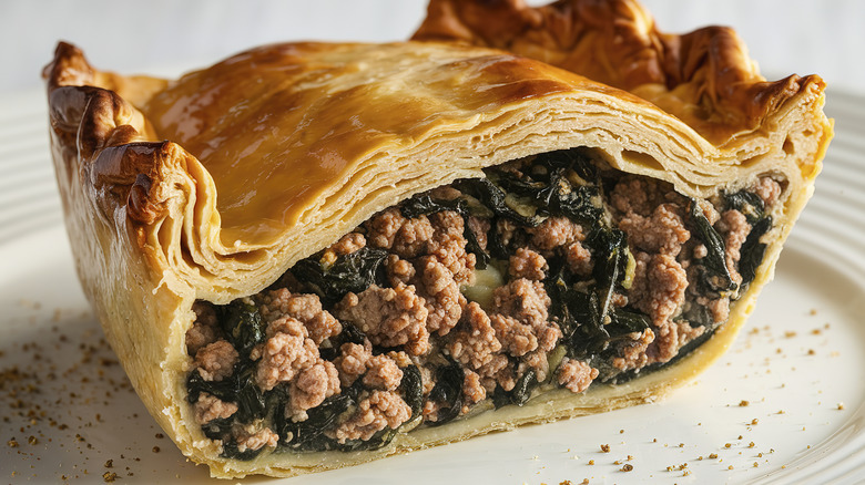 An overstuffed spinach and meat pie cut in half