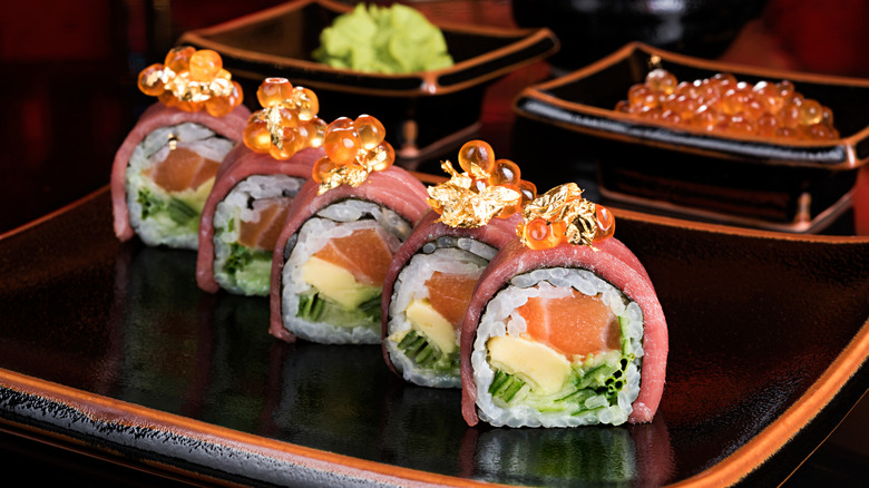 A colorful sushi roll on a black dish