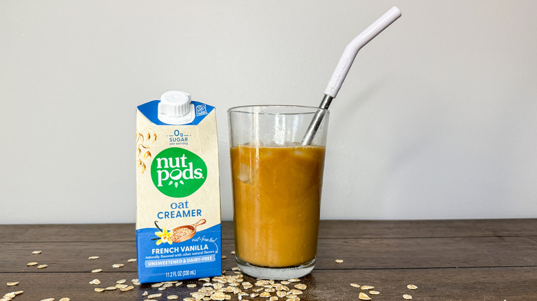 Carton of Nutpods oat creamer next to glass of iced coffee