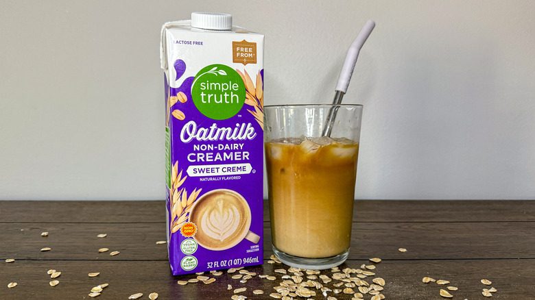 Carton of Kroger Simple Truth Oat Milk creamer next to glass of iced coffee