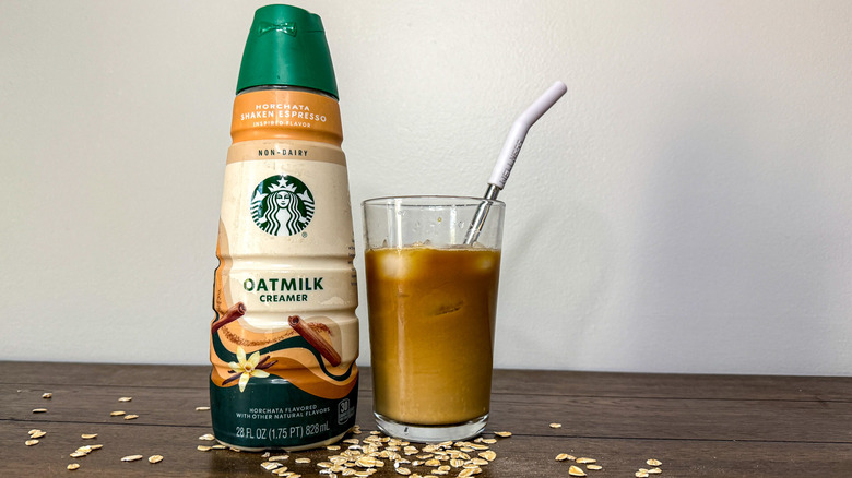 Bottle of Starbucks Horchata non-dairy oat milk creamer next to glass of iced coffee