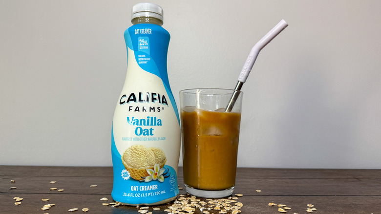 Bottle of Califia Farms Vanilla Oat creamer next to a glass of iced coffee
