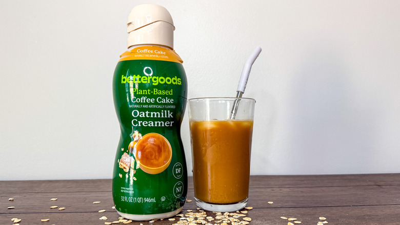 Container of Walmart Better Goods Oat Milk Creamer next to a glass of iced coffee