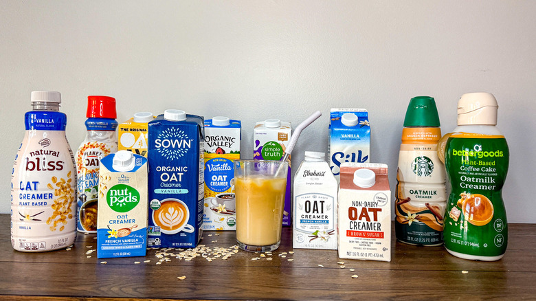 Bottles and cartons of oat milk creamer arranged around a glass of iced coffee