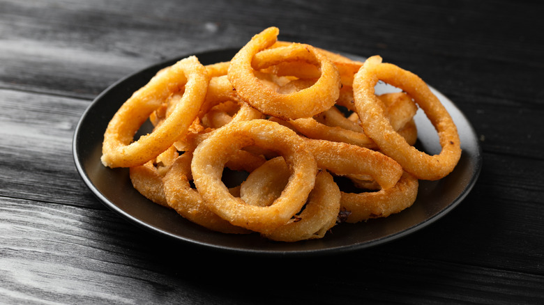a serving of onion rings on a black plate