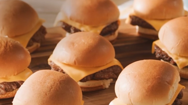A platter of cheeseburger sliders on a wooden tray