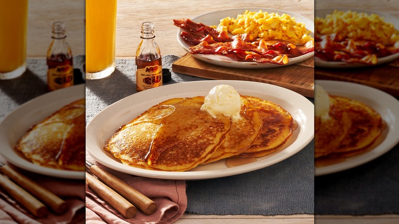 A plate of pancakes with eggs, bacon, and syrup
