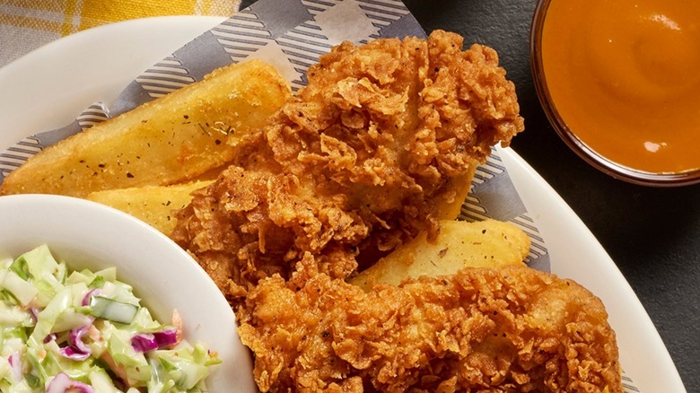 A plate with chicken tenders, fries, and dipping sauces
